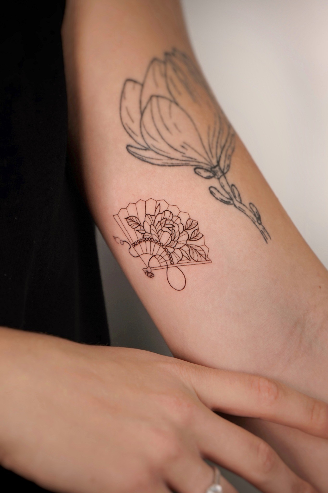 Tatuaje fineline de abanico floral en el brazo realizado por Shira Tattoo