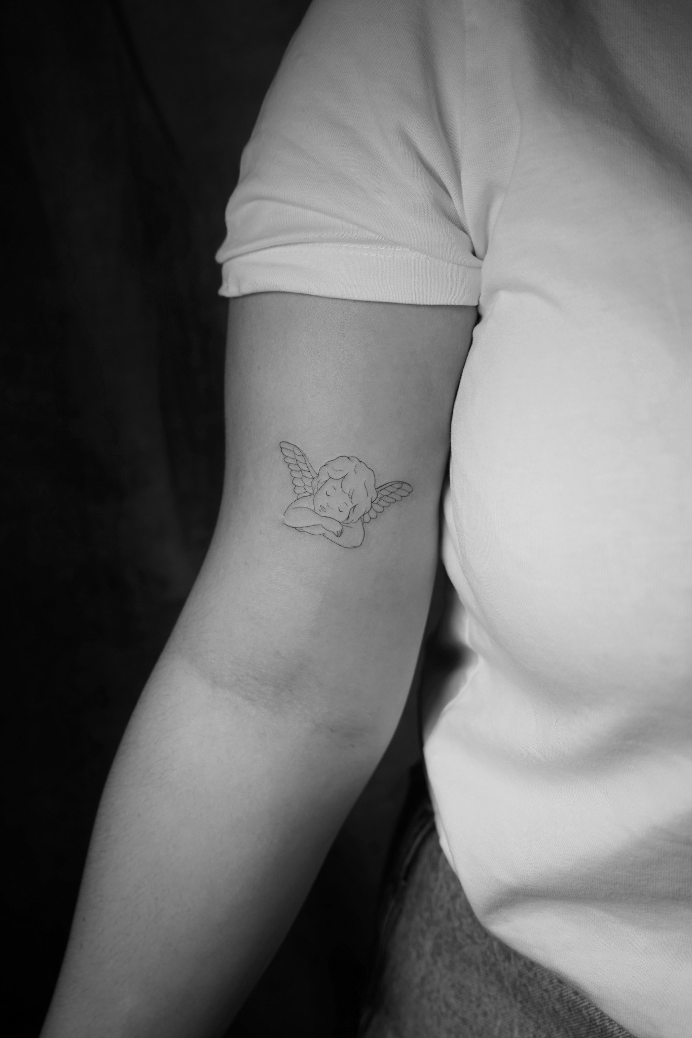 Tatuaje fineline de ángel pequeño en el brazo realizado por Shira Tattoo