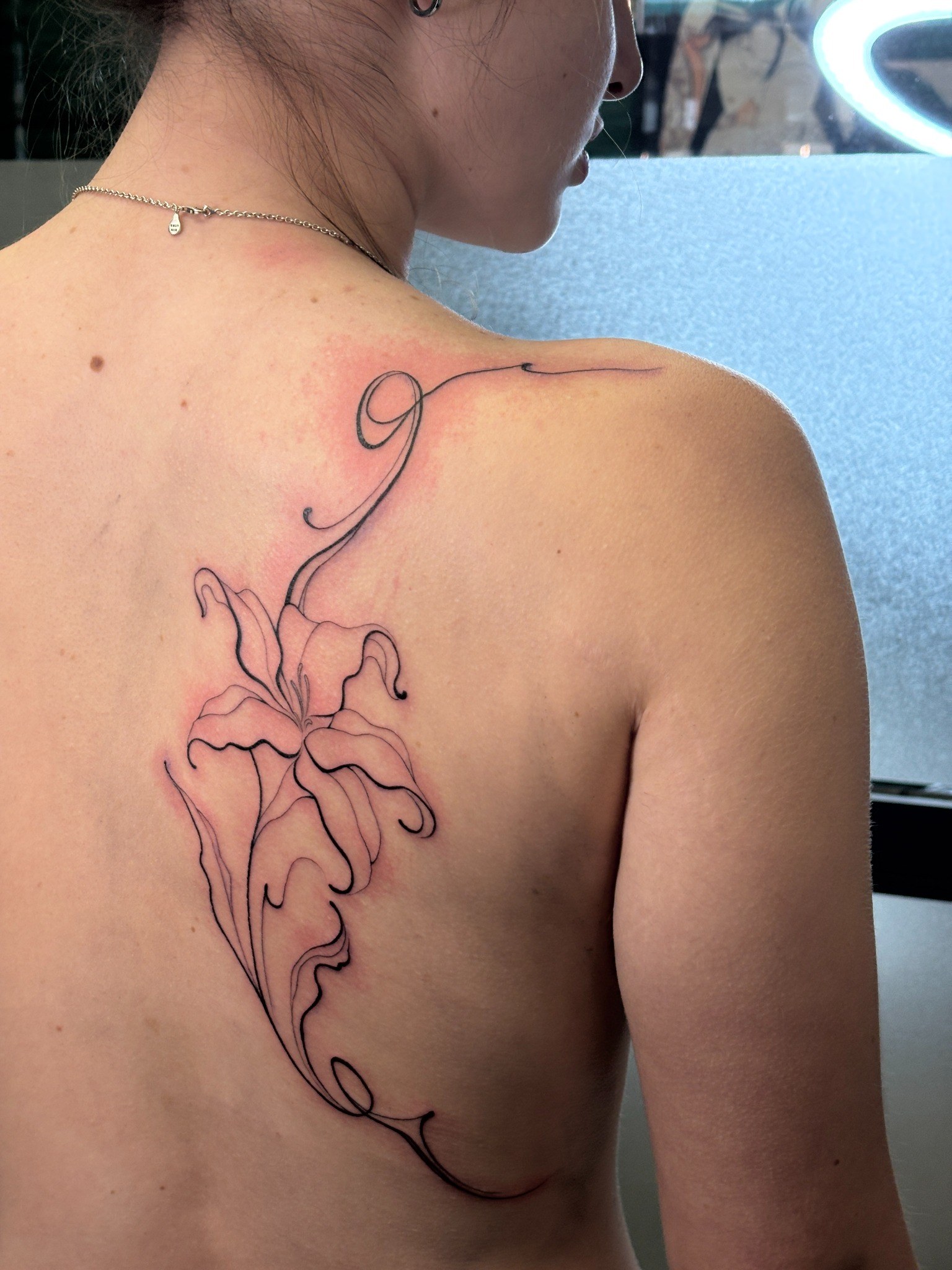 Tatuaje fineline floral de gran formato en la espalda realizado por Shira Tattoo