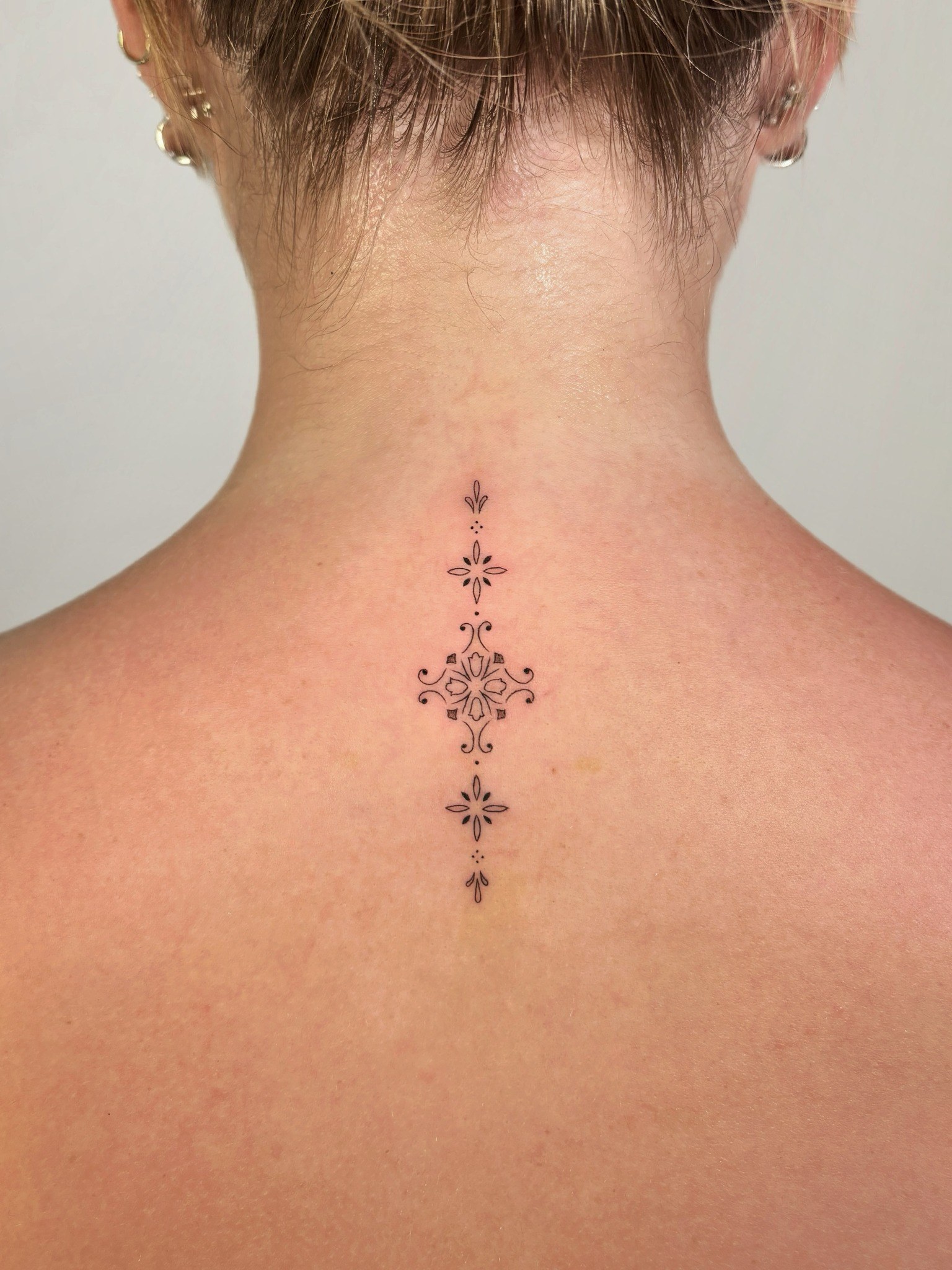 Tatuaje fineline ornamental en la nuca realizado por Shira Tattoo