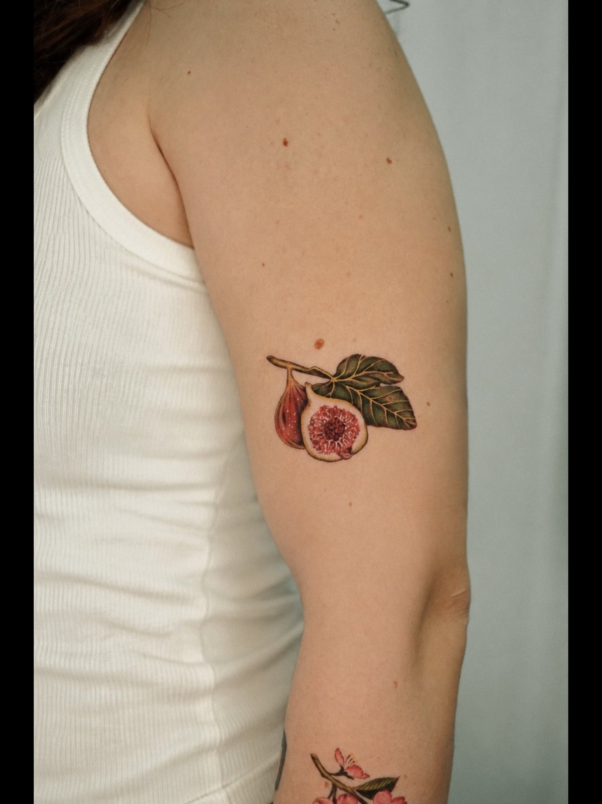Higos y hojas en microrealismo a color sobre el brazo