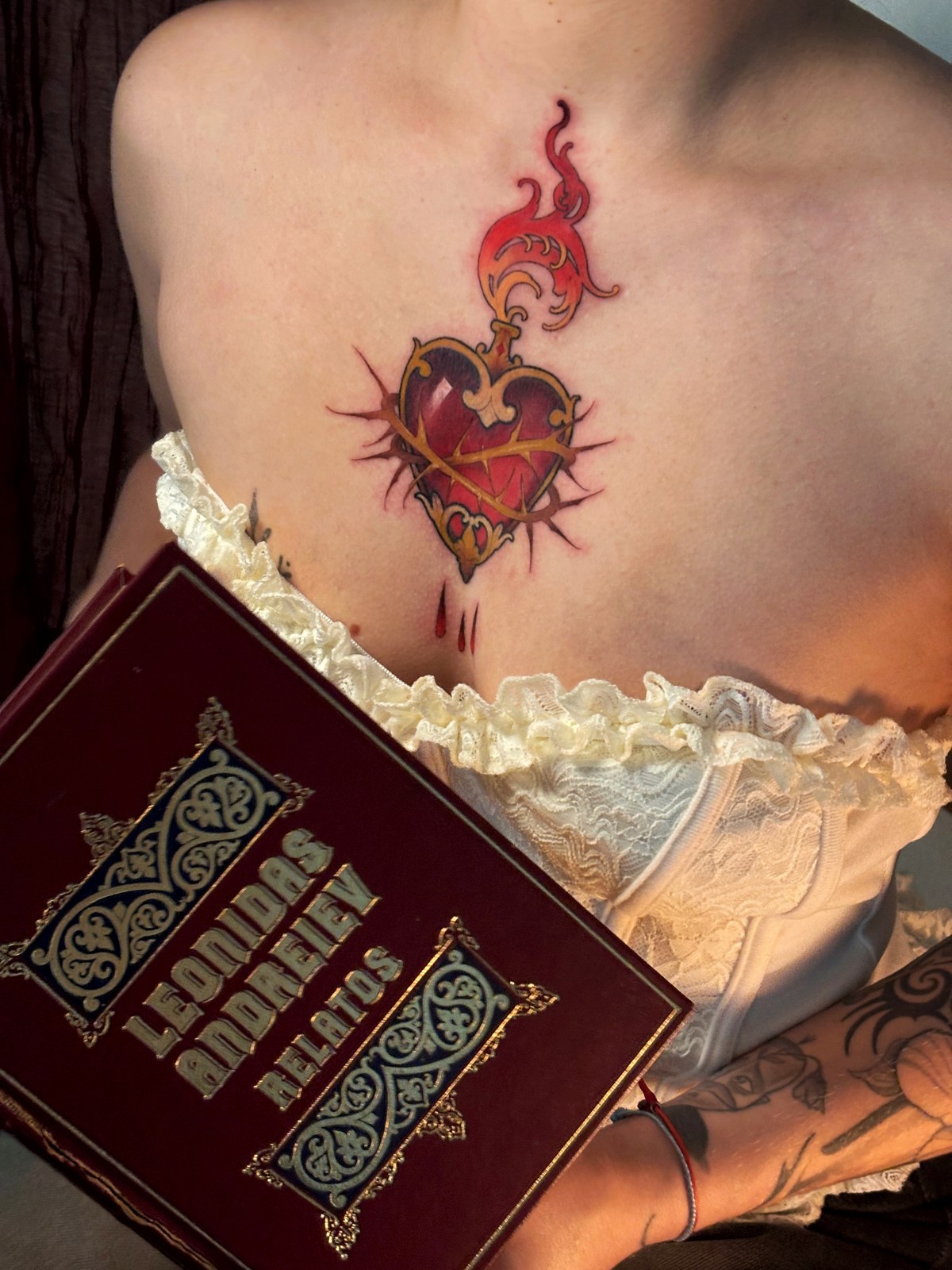 Corazón neotradicional rojo y dorado, junto a un libro y encaje crema